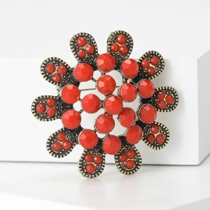 Broche tournesol vintage dorée avec strass rouges sur un support blanc épuré