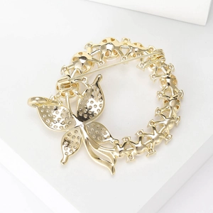 Macro shot of the gold butterfly wreath brooch showing the secure safety pin closure