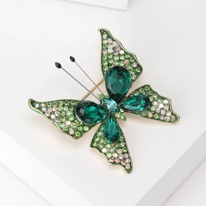 Detailaufnahme einer Brosche in Schmetterlingsform mit grünen Kristallen und Diamantbesatz