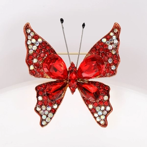 Makroaufnahme der Schmetterlingsbrosche mit roten Tropfenkristallen und Glitzersteinen