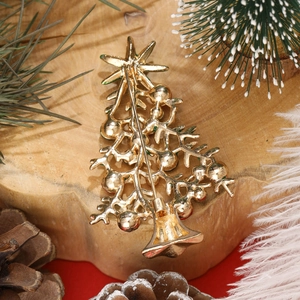 Broche sapin de Noël dorée avec fermeture de sécurité sur bois et fond rouge festif