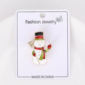 Détail d'une broche bonhomme de neige émaillée avec écharpe rouge sur carte bijoux