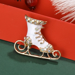 Detalle del broche de patín de hielo dorado con esmalte blanco y brillantes diamantes