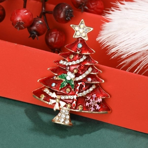 Elegante spilla ad albero di Natale con strass colorati su sfondo di confezione regalo rossa