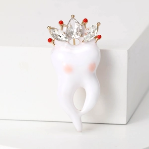 Broche créative en forme de dent avec couronne et strass sur socle blanc