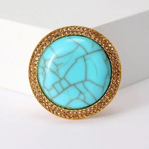 Detail of bohemian round brooch with large faux turquoise and champagne rhinestones