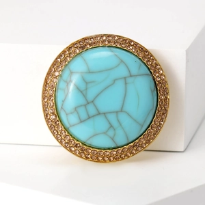 Detail shot of vintage flower brooch featuring turquoise stone and champagne rhinestones