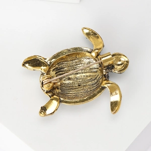 Vintage gold turtle brooch with back pin safety clasp on white geometric display stand