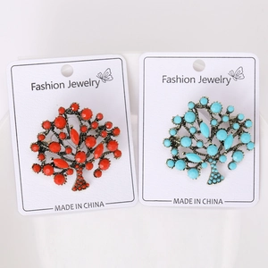 Detail view of retro gold tree brooches with red and turquoise resin gemstones