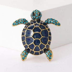 Detailed close-up of blue enamel turtle brooch with gold plating and sparkling crystals