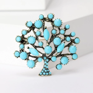 Detailed close-up of a vintage bronze tree brooch with turquoise stones on white background