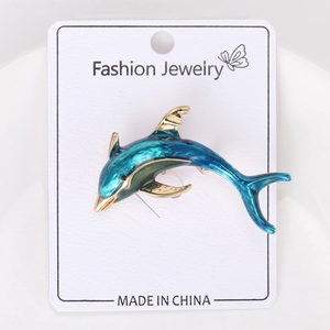 Detail of blue gradient enamel dolphin brooch with golden fins on jewelry card