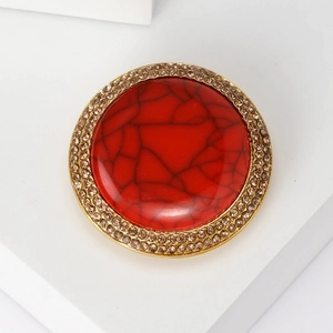Macro detail of vintage floral brooch with large red marble stone and champagne crystals