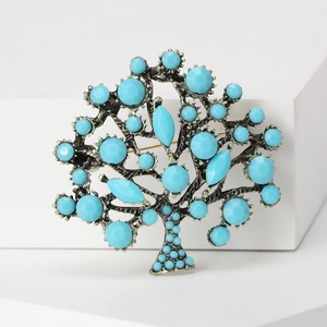 Vintage bohemian style tree of life brooch with turquoise beads on white background