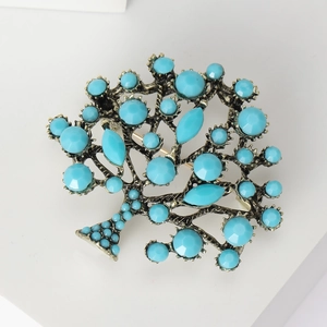 Close-up of vintage tree brooch with turquoise stones and a bronze metallic frame