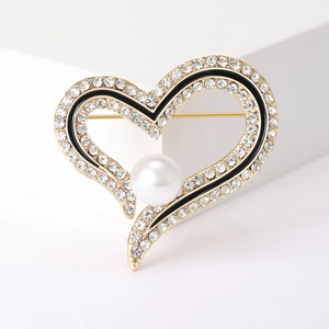 Détail d'une broche en cœur avec cristaux, émail noir et une perle blanche élégante