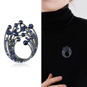 Close-up of elegant rhinestone brooch with blue crystals on black knitwear