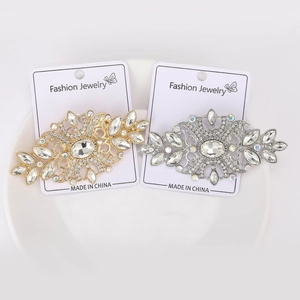 Detailed macro view of vintage gold and silver crystal encrusted brooches on card