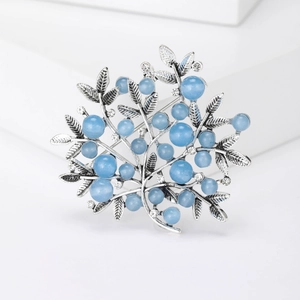 Detailed view of a silver branch brooch with light blue beads and sparkling crystals