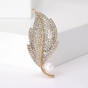 Elegant gold leaf brooch with sparkling crystals and a white pearl on white background
