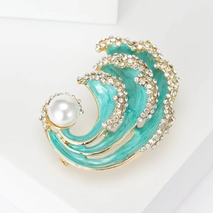 Macro detail of wave brooch with turquoise enamel, sparkling crystals, and white pearl