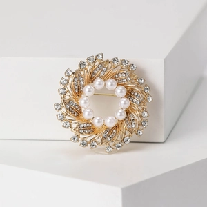 Detailed close-up of crystal wreath brooch with white pearls on a minimalist pedestal