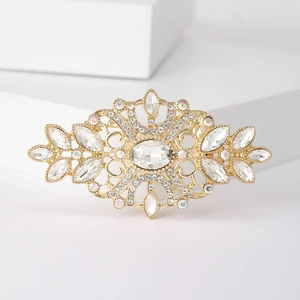 Vintage gold crystal brooch with radiant diamond pattern on white geometric pedestal