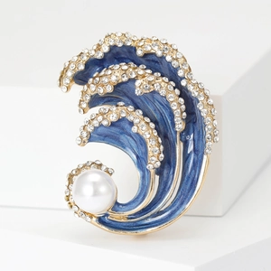 Macro detail of wave brooch with blue enamel inlay, sparkling crystals, and white pearl