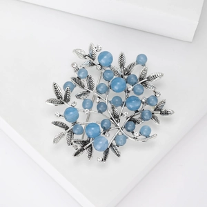Close-up of vintage berry brooch with blue gems and rhinestones on a display stand
