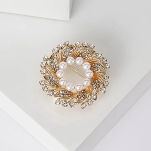 Close-up of a floral wreath brooch with white pearls and sparkling rhinestones