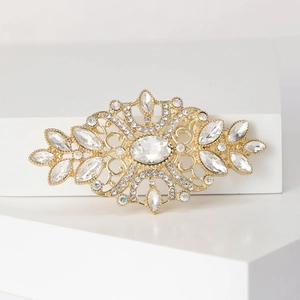 Detail of vintage gold crystal brooch with marquise stones on white geometric stand