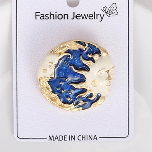 Detail view of moon and sun brooch with blue enamel on a white display card