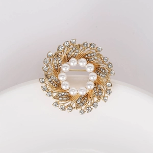Detailed macro shot of a golden wreath brooch with white pearls and sparkling crystals