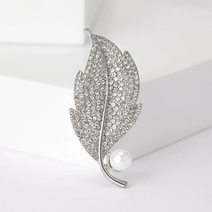 Macro shot of leaf-shaped silver brooch with pave crystals and white pearl accent