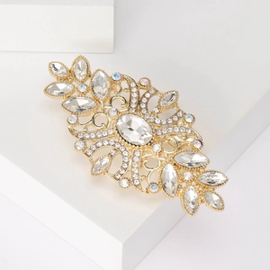 Detailed side view of vintage gold hair clip with crystals on a white stone pedestal