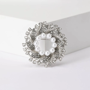Close-up of silver floral brooch with white pearls and sparkling rhinestones on base