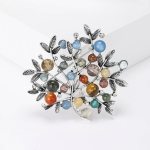 Macro detail of a silver tree branch brooch featuring assorted colorful gemstone beads