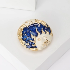 Detailed view of sun and moon vintage enamel brooch with gold frame and blue starry night sky