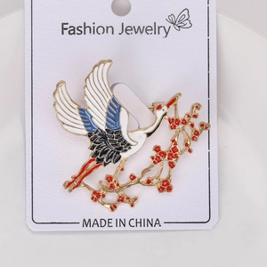 Detailed close-up of crane and plum blossom enamel brooch with gold-plated alloy finish