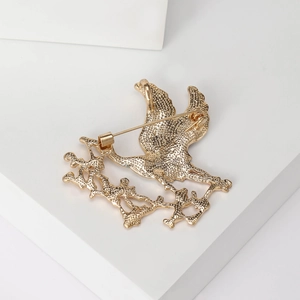 Golden crane brooch with textured metal finish and secure pin clasp on a white background