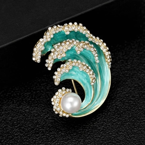 Macro detail of blue enamel ocean wave brooch with pearls and inlaid rhinestones