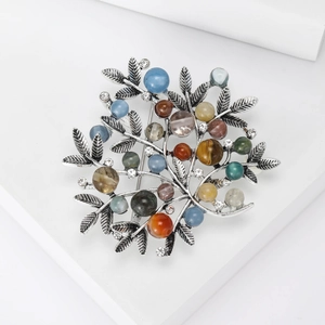 Close-up of vintage branch brooch with colorful beads and leaf texture details