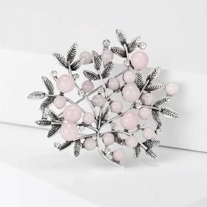 Macro detail of silver alloy leaf textures and pink pearls on a nature-inspired brooch