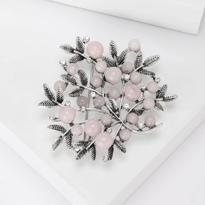 Macro view of vintage silver plant brooch with pink pearls and white zircons