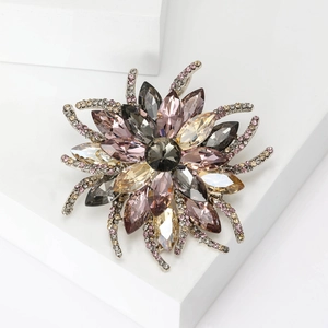 Broche florale étincelante avec cristaux gris et roses sur fond de pierre géométrique