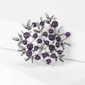 Detail of silver alloy branch brooch featuring purple beads and sparkling rhinestones