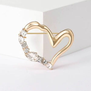 Elegante spilla a cuore dorata con cristalli scintillanti su espositore bianco