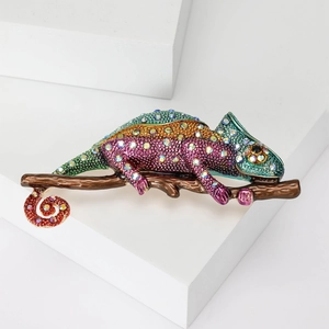 Detailed close-up of a large chameleon brooch with colorful rhinestones on a brown branch