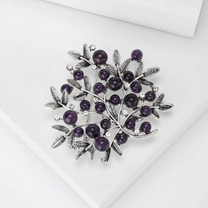 Detail view of retro berry branch brooch with purple beads and silver metal leaves