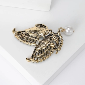 Vintage hollow alloy butterfly brooch with pearl pendant on a white geometric block